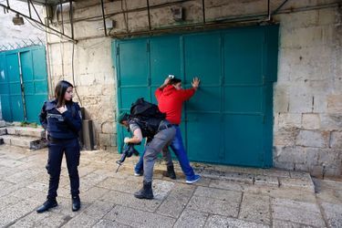 Un policier israélien fouille un palestinien après l'attaque du garde-frontière. 
