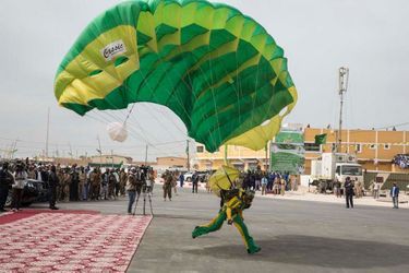 C'est l'apothéose du défilé avec le saut de 14 parachutistes qui, en deux vagues successives, se posent juste devant la tribune présidentielle.Grande première à Nouadhibou pour la fête nationale : à l'occasion  du 55ème anniversaire de l'indépendance de la Mauritanie, ce 28 novembre, un grand défilé militaire est organisé pour la première fois dans cette ville située à quelques encablures du Cap Blanc. Il durera plus de 2 h 30 avec plus de 5.000 militaires et membres des forces de sécurité du pays.Mauritanie: Avec le président Aziz dans la "zone rouge" du désert<br />
Comme pour mieux marquer l'identité de cette jeune République, toute la ville de Nouadhibou est pavoisée de jaune et vert et mobilisée pour fêter ses forces armées, auxquelles la population réserve un excellent accueil. Tout au long de cette impressionnante parade, on se croirait sur les Champs Elysées et même place de la Concorde pour le lâché de parachutistes final comme le 14 Juillet<br />
 à Paris.C'est le président Mohamed Ould Abdel Aziz – lui-même ancien général – qui a décidé cette année de décentraliser pour la première fois l'événement pour mieux mobiliser autour de lui la Nation qui se veut « un rempart » contre le terrorisme djihadiste frappant tous les jours dans les pays frères du Sahel<br />
. Plusieurs contingents des pays membres du G5-Sahel, comme des soldats maliens, sénégalais et tchadiens, participent également à ce grand défilé destiné à marquer les esprits dans toute l'Afrique.Bruno Fanucchi 