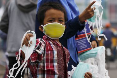 Un enfant indonésien distribue des masques pour éviter la pollution des rues de Palembang. 