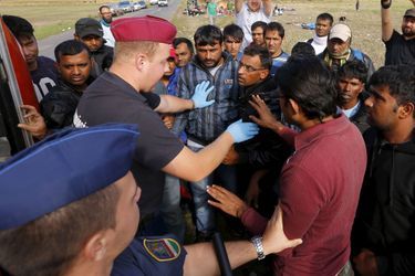 Des policiers hongrois contrôlant des migrants syriens. 