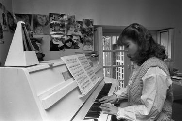 Marie Trintignant étudiant le piano, au mur des photos d&#039;elle avec ses parents Nadine et Jean-Louis Trintignant et des photos de son petit frère Vincent. Photo prise en 1978.