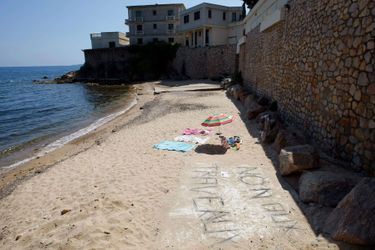La plage de la discorde : un graffiti dénonçant les travaux apparaît au premier plan.