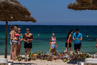 Des touristes devant les fleurs déposées sur la plage de Sousse en mémoire des victimes de l'attentat. 