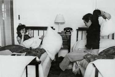 Romy SCHNEIDER et Alain DELON faisant une bataille de polochons, assis sur des lits jumeaux dans une chambre à Paris au début des années 60.