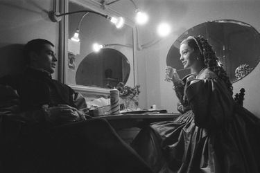 La pièce "Dommage qu'elle soit une p..." mise en scène par Luchino VISCONTI au théâtre de Paris : Romy SCHNEIDER un verre d'eau à la main assise devant la coiffeuse de sa loge, discutant avec Alain DELON tous deux en costumes de scène.