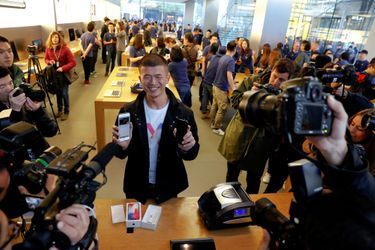 Le premier client a avoir obtenu un iPhone X montre son nouveau jouet, dans un Apple Store de Pékin, en Chine.