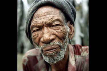 <br />
Besa, un chamane bushman, avec ses deux petits-fils.<br />
Les Bushmen sont les plus anciens habitants de lʼAfrique australe. Au cours des siècles, ce peuple nomade de chasseurs<br />
cueilleurs a été décimé par lʼarrivée successive des Hottentos et des Bantous qui les ont repoussés vers des terres de plus en plus ingrates, dans le désert du Kalahari. Entre 1997 et 2002, de nombreux Bushmen ont été expulsés de leurs terres de la réserve de gibier du Kalahari central et déportés dans des camps de relocalisation situés en dehors de la réserve.<br />
En réaction, les Bushmen intentèrent un procès au gouvernement botswanais et en 2006, avec le soutien de Survival<br />
International qui lança une campagne internationale en leur faveur, ils remportèrent une victoire historique en gagnant le droit de retourner chez eux.<br />
Cependant, dʼautres communautés bushmen sont aujourdʼhui menacées dʼexpulsion dans le cadre du projet de création dʼun ʻcorridor écologiqueʼ.Nous avons été créés comme le sable, nous sommes nés ici, dit un Bushman. Ce lieu est la terre du père du père de mon père.