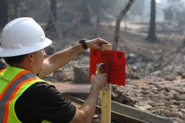 «Dangereux» : un fonctionnaire agrafe une pancarte sur les ruines laissées par l'incendie, à Napa, vendredi.