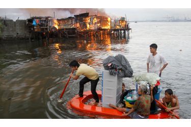 Des résidents pagayent dans leur bateau de fortune alors que leur maison est dévastée par un incendie à Manille, aux Philippines. En mai 2012, près de 1000 maisons ont été détruites par les flammes. 5000 familles se sont retrouvées sans foyer d&#039;après les médias locaux.