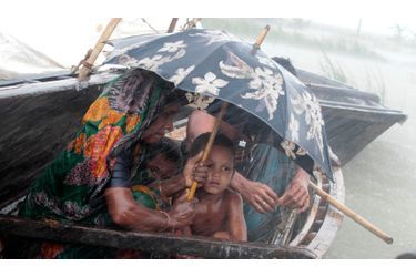 Une femme tente de protéger son enfant des pluies diluviennes qui s&#039;abattent sur le village de Kurigram, au Bangladesh. Au moins 100 personnes ont trouvé la mort et des centaines de milliers de résidents ont été livrés à eux-même lors de ces inondations.