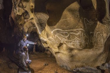Dans la Salle Hillaire, devant le panneau des Grandes Gravures, le préhistorien Jean Clottes, directeur scientifique de la Grotte Chauvet de 1998 à 2006 et David Huguet, membre du comité scientifique de la Grotte Chauvet observent le panneau du Cheval Gravé.