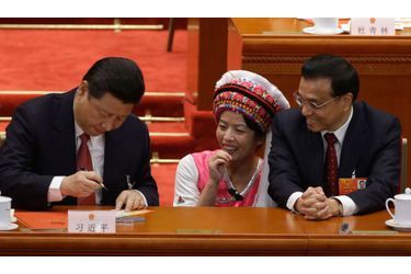 Le Premier ministre chinois Li Keqiang et une déléguée d’une des minorités ethniques regardent le nouveau président chinois signer un autographe pendant le Congrès National du Peuple.