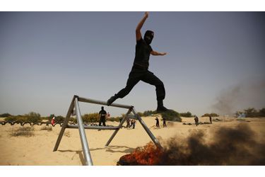 Un militant palestinien du Front Populaire pour la Libération de la Palestine (FPLP) saute par-dessus un pneu en feu lors d’une manifestation dans le sud de la bande de Gaza. 