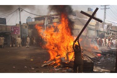 Un manifestant brûle une croix pendant une manifestation dans la banlieue de Badami Bagh, au Pakistan. La foule, en colère, a incendié des dizaines de maisons dans le quartier chrétien de Lahore.