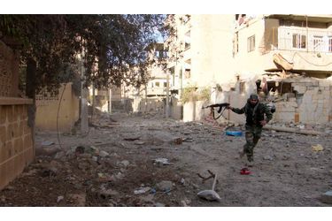Un combattant de l&#039;Armée syrienne libre tente de se couvrir en tirant derrière lui à Deir al-Zor, en Syrie, jeudi.