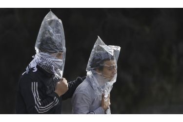 Deux manifestants tentent de se protéger des gaz lacrymogènes avec des sacs plastiques, au Caire, lundi.