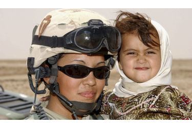 Janie Reyna, membre de la 56ème brigade de combat de la 36ème division d’infanterie de l’armée américaine porte dans ses bras une petite fille rencontrée lors de l’une de ses missions dans le sud de l’Irak. 