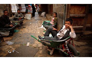 Des hommes et des enfants attendent l'arrivée de livraisons au marché de Sanaa, au Yémen.
