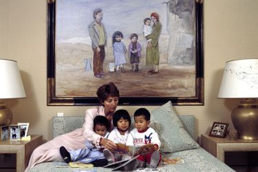 Marina Picasso avec ses trois enfants vietnamiens, dans une chambre de sa villa "La Californie", devant un tableau de son grand-père Pablo Picasso. 1992. 