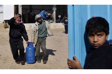 Des Palestiniens portent des bonbonnes de gaz après les avoir remplies dans une station-service de la bande de Gaza.  