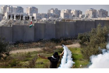 Un Palestinien utilise un lance-pierres pour renvoyer une grenade lacrymogène tirée par des agents de sécurité israéliens (à l'arrière) lors d'affrontements après un rassemblement marquant le 48ème anniversaire du Fatah, dans le village de Bilin en Cisjordanie, près de Ramallah.