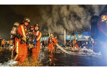 Des pompiers sortent un homme des flammes. Dimanche soir, un marché de produits agricoles a pris feu à Shanghai, en Chine, faisant au moins six morts et dix blessés. 