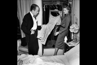  1951 - Lauren Bacall et Humphrey Bogart sont en vacances à Paris. Bogart veut montrer la Ville Lumière aux plus beaux yeux d&#039;Amérique . Dans leur appartement de l&#039;hôtel Ritz ils se sont efforcés de recréer dès leur arrivée une atmosphère familière. Les murs sont tapissés de photos de leur fils Stephen, et de leur villa de Beverly Hills. Dans l&#039;intimité Humphrey appelle Lauren &quot; Baby&quot; et elle l&#039;appelle &quot;Bogie&quot;. Sur la photo Lauren a sorti de ses malles cinq tailleurs, deux robes noires de dîner et un manteau de vison. 
