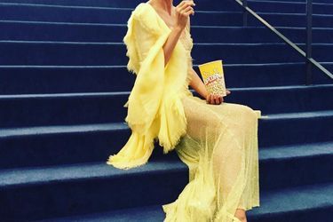 Le mannequin Heidi Klum mange du popcorn assorti à sa robe Versace vaporeuse.