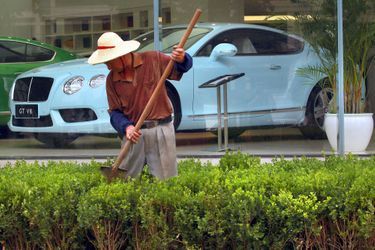 Un jardinier s&#039;affaire devant une concession Bentley à Pékin, en Chine.