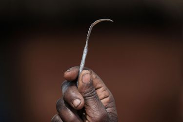 Une femme brandit son outil d'excision, au Ouganda