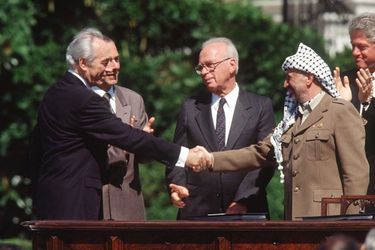 Shimon Peres serre la main de Yasser Arafat sous les yeux d&#039;Yitzhak Rabin, en 1993, après la signature des accords d&#039;Oslo.