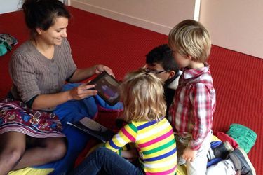 Léna Mazilu jouant avec des enfants en lisant le livre numérique «Chouette».