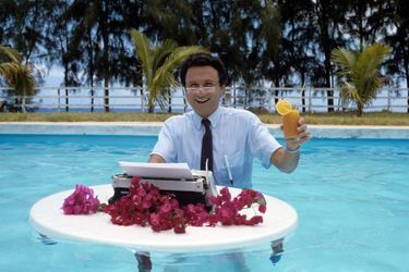 La Réunion, 1987 : Michel Drucker devant sa machine à écrire dans une charmante piscine.