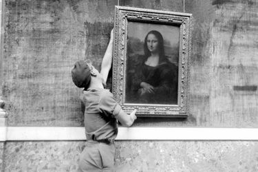 Un employé du musée accroche le célèbre portrait de Mona Lisa plus connu sous le nom de "La Joconde", peinture de Léonard de Vinci (1452-1519), le 6 octobre 1947, lors de la réouverture de la grande galerie du musée du Louvre.