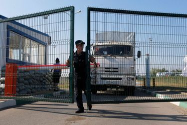 Un garde-frontière russe ouvre la porte pour laisser passer le camion humanitaire, dans la région frontalière de Rostov.