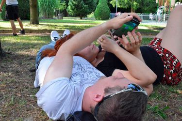 Deux Français jouent à Pokémon Go, allongés dans un parc