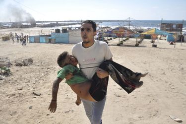 Un homme portant le corps de l'un des quatre enfants tués mercredi sur une plage de Gaza.