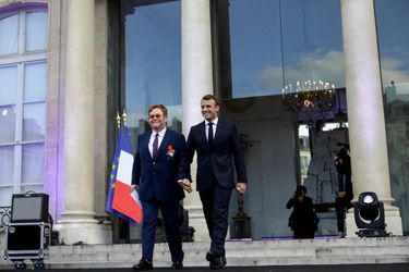Elton John, tout juste décoré de la Légion d'honneur, et Emmanuel Macron arrivent main dans la main sur la scène. 