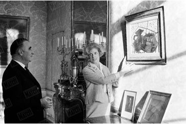 Le Premier Ministre Georges Pompidou regarde son épouse Claude accrocher le tableau "Le tapis vert" de Georges Braque dans les appartements privés de Matignon, en décembre 1962.