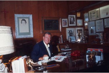 John Wayne dans le bureau de sa villa, à Newport Beach, Californie, en juin 1967. Au mur, parmi ses plus beaux trophées, une photo dédicacée d'Eisenhower.