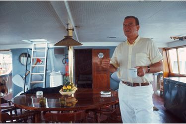 « John Wayne en pantalon blanc de “captain” a bord de son yacht de quarante-cinq mètres l'“Oie sauvage”, un ancien dragueur de mines. Depuis son opération, Wayne ne boit plus que du café, dans des tasses marquées au prénom de sa femme. » - Paris Match n°951, 1er juillet 1967.