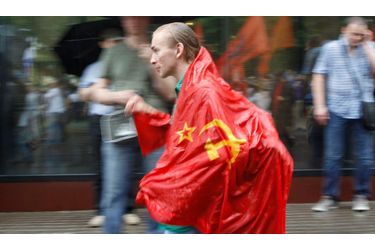 Un militant se balade avec le drapeau soviétique sur lui, sous la pluie, pendant le rassemblement.