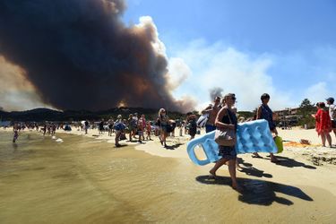 Des touristes quittent la plage alors que le feu brûle la forêt à Bormes-les-Mimosas