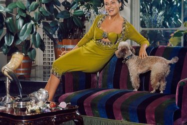 Jeanne Moreau assise sur un canapé chez son compagnon Pierre Cardin, habillée d&#039;une robe verte, présentant la mode Cardin 1964.