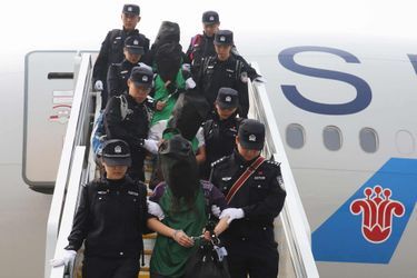 La police escorte un groupe de personnes accusées de fraudes en Chine, après avoir été expulsés du Kenya, à leur arrivée à l&#039;aéroport de Pékin le 13 avril. 