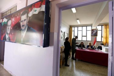 Un bureau de vote à Damas, paré d&#039;une affiche de Bachar al-Assad et son père Hafez.