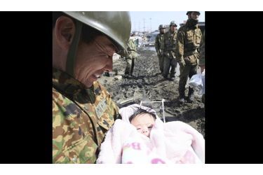 Un militaire tient dans ses bras un nourrisson de quatre mois, dans la ville d&#039;Ishimaki.