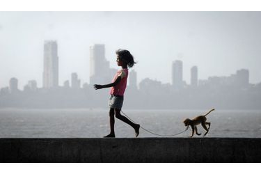 Une fillette se promène avec un singe de compagnie, à Bombay.