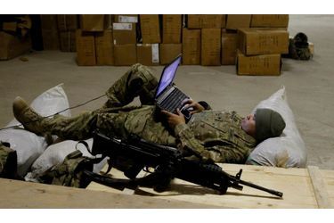 Un soldat américain se repose sur des sacs et utilise son ordinateur portable, après une patrouille dans la province de Nangarhar, dans l’est de l’Afghanistan.