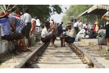 Des hommes, assis sur une voie ferrée, discutent ensemble alors qu&#039;ils attendent leur train à destination de Rangoun en Birmanie.